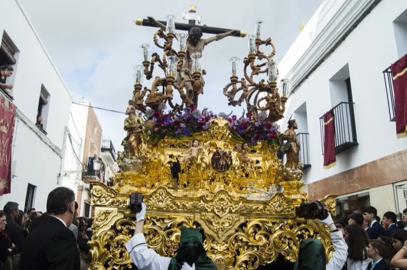 El paso del Stmo. Cristo de la Vera-Cruz, dorado y con flores moradas, en la calle