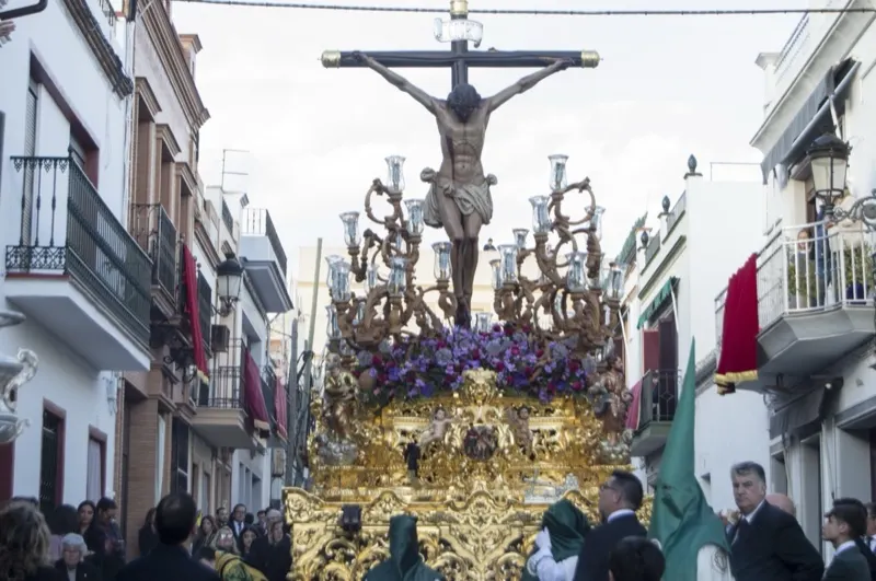 El paso del Stmo. Cristo de la Vera-Cruz por una calle de El Viso del Alcor, entre balcones con colgaduras